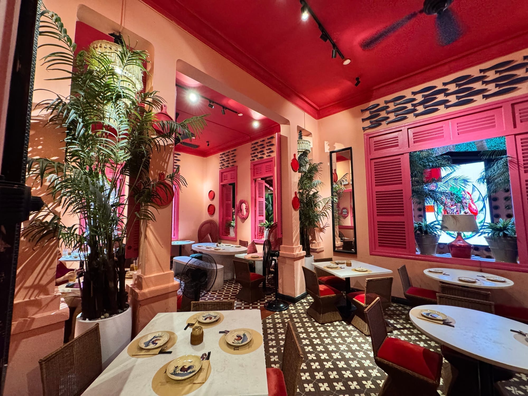 Vibrant interior of Nhà Hàng Ngon with pink and red walls, dining tables, and lush decorative plants